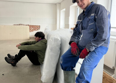 Muži v pracovnom oblečení pri príprave materiálu v sklade.