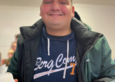 Portrét usmievavého muža v zimnej bunde držiaceho misku s jedlom.