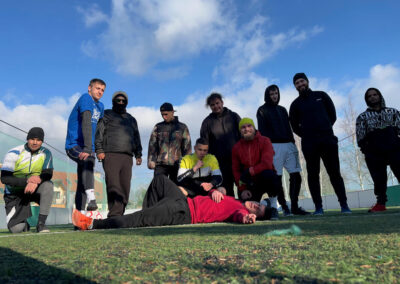 Skupinová fotka tímu na futbalovom ihrisku s umelou trávou.